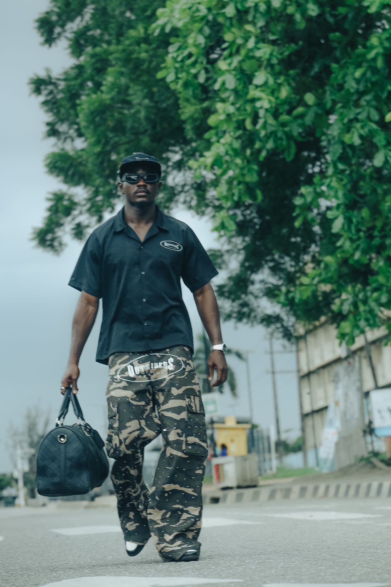 Walking in camo trousers with a black duffel bag