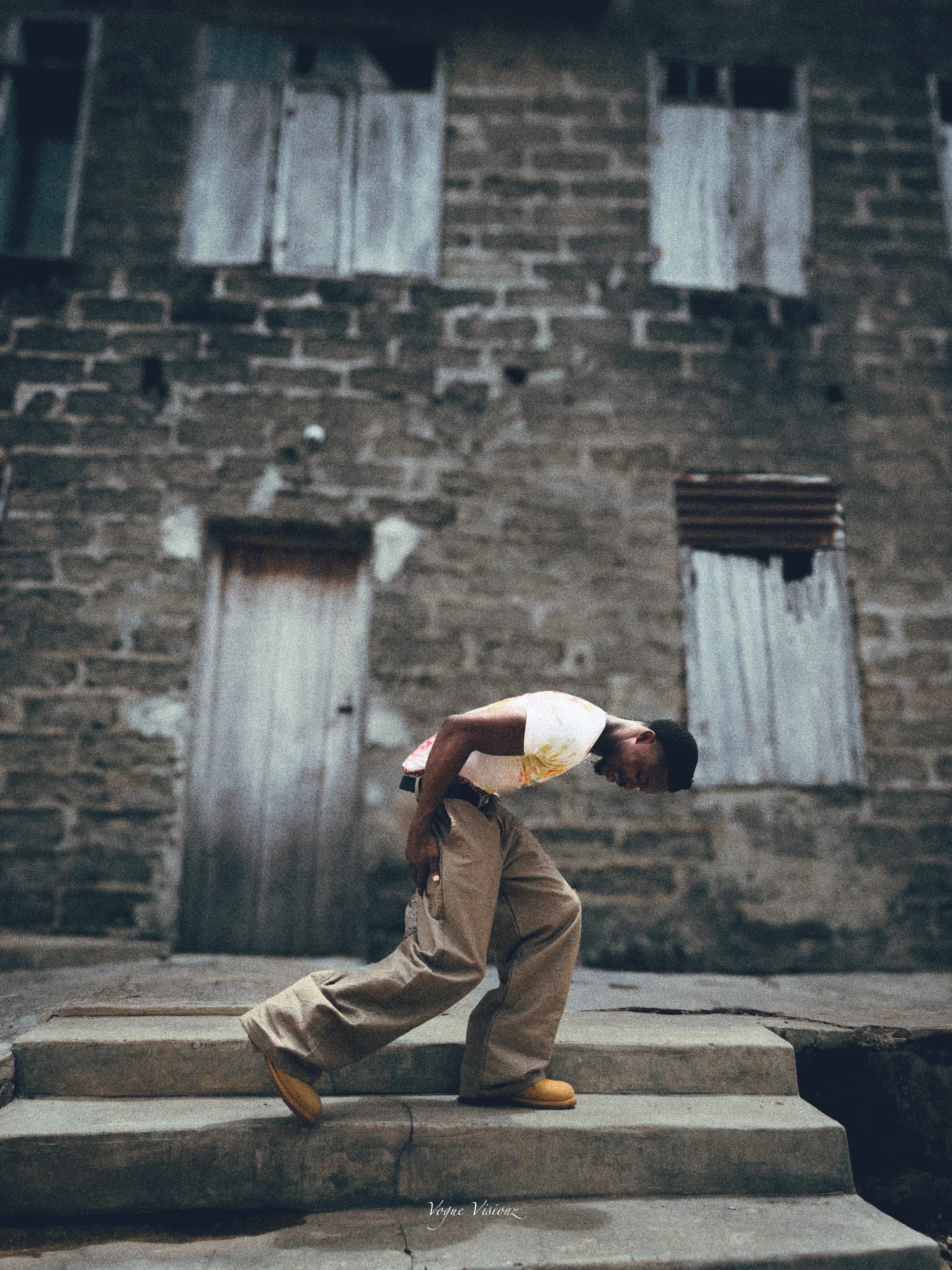 Bent pose on stone steps in khaki wide-leg trousers