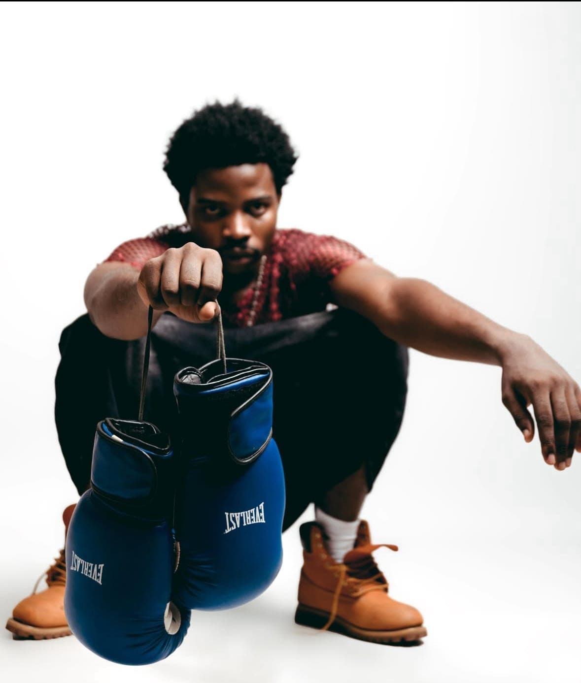 Crouching pose holding blue boxing gloves, tan boots
