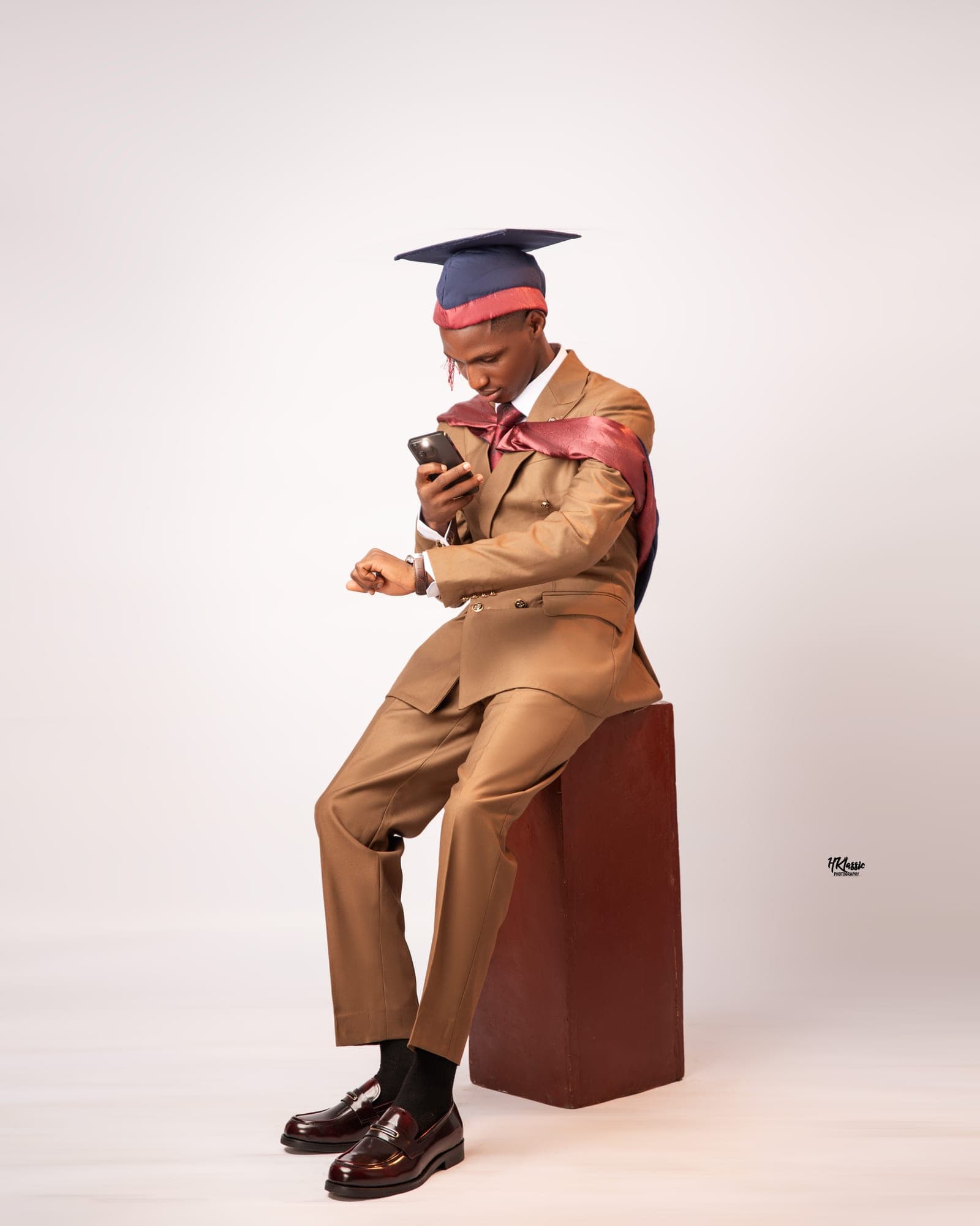 Camel suit with graduation cap, seated on a red block