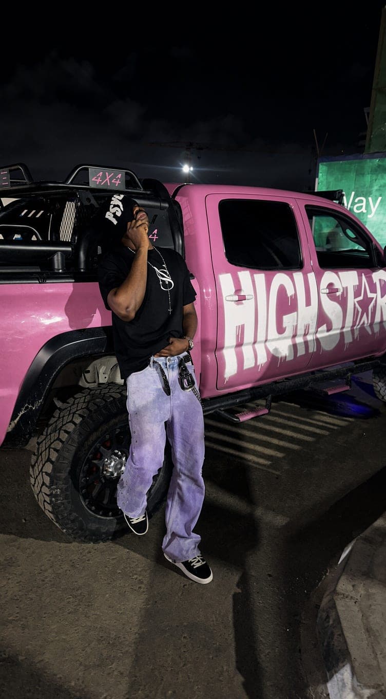 Lilac jeans and black tee against a pink truck at night