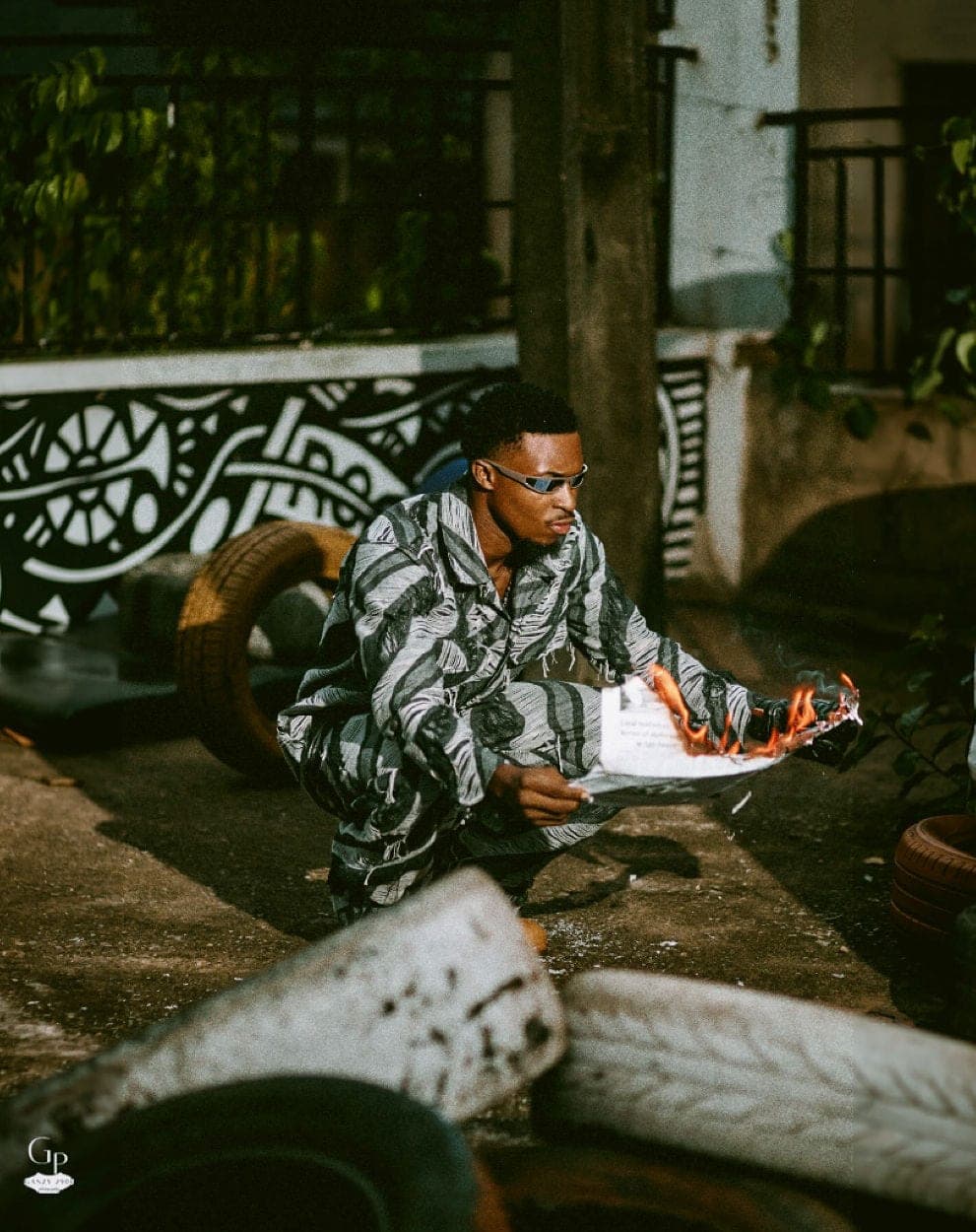 Striped two-piece set, reading a newspaper among tyres